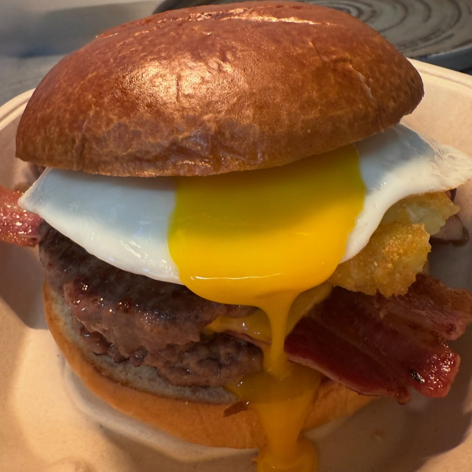 Shakey J's smash burger topped with a fried egg and bacon